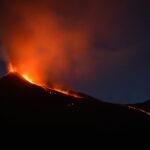 black mountain with flowing lava at nighttime