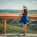 woman in blue sleeveless dress wearing white hat standing on brown wooden bridge during daytime