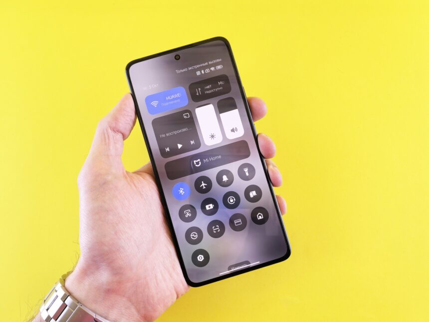Hand holding smartphone with control panel on screen