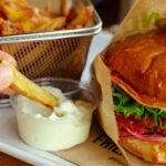 burger with cheese and vegetable on stainless steel tray