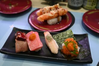 Assortment of sushi and sashimi on a black plate.
