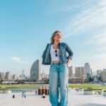 Woman standing on rooftop with city skyline behind her