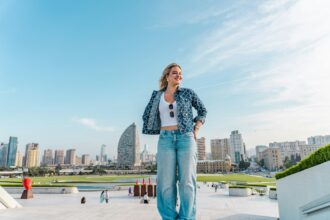 Woman standing on rooftop with city skyline behind her