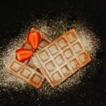 Tasty Belgian waffles topped with fresh strawberries and sugar dusting.