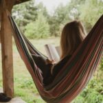 woman reading book on hammock
