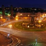 a city intersection at night with a clock tower in the background