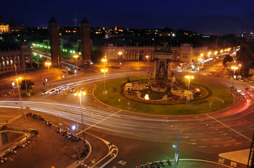 a city intersection at night with a clock tower in the background