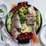 a platter of fish, tomatoes, cucumbers, avocado,